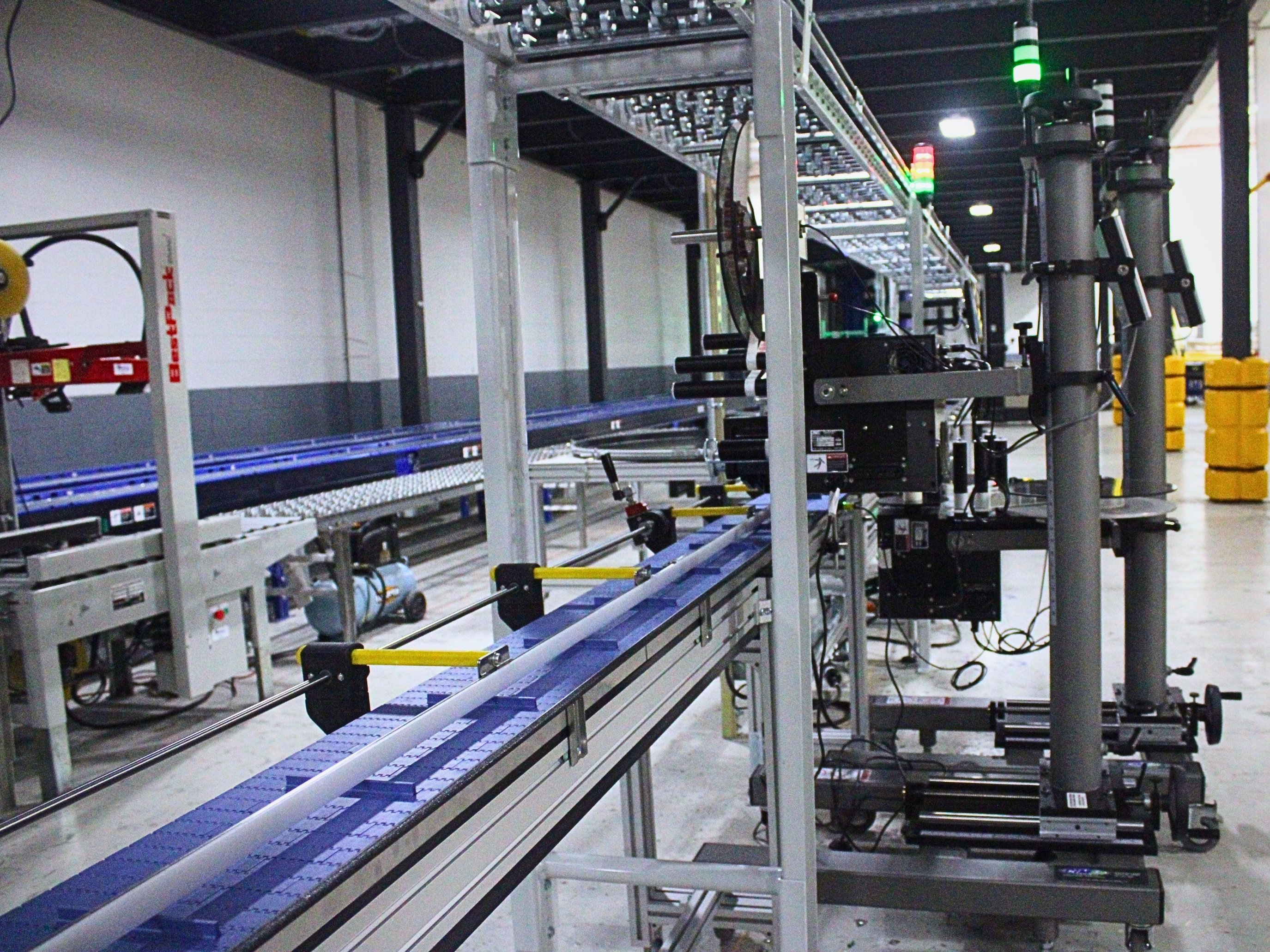 Product conveyor passing through automated labeling equipment
