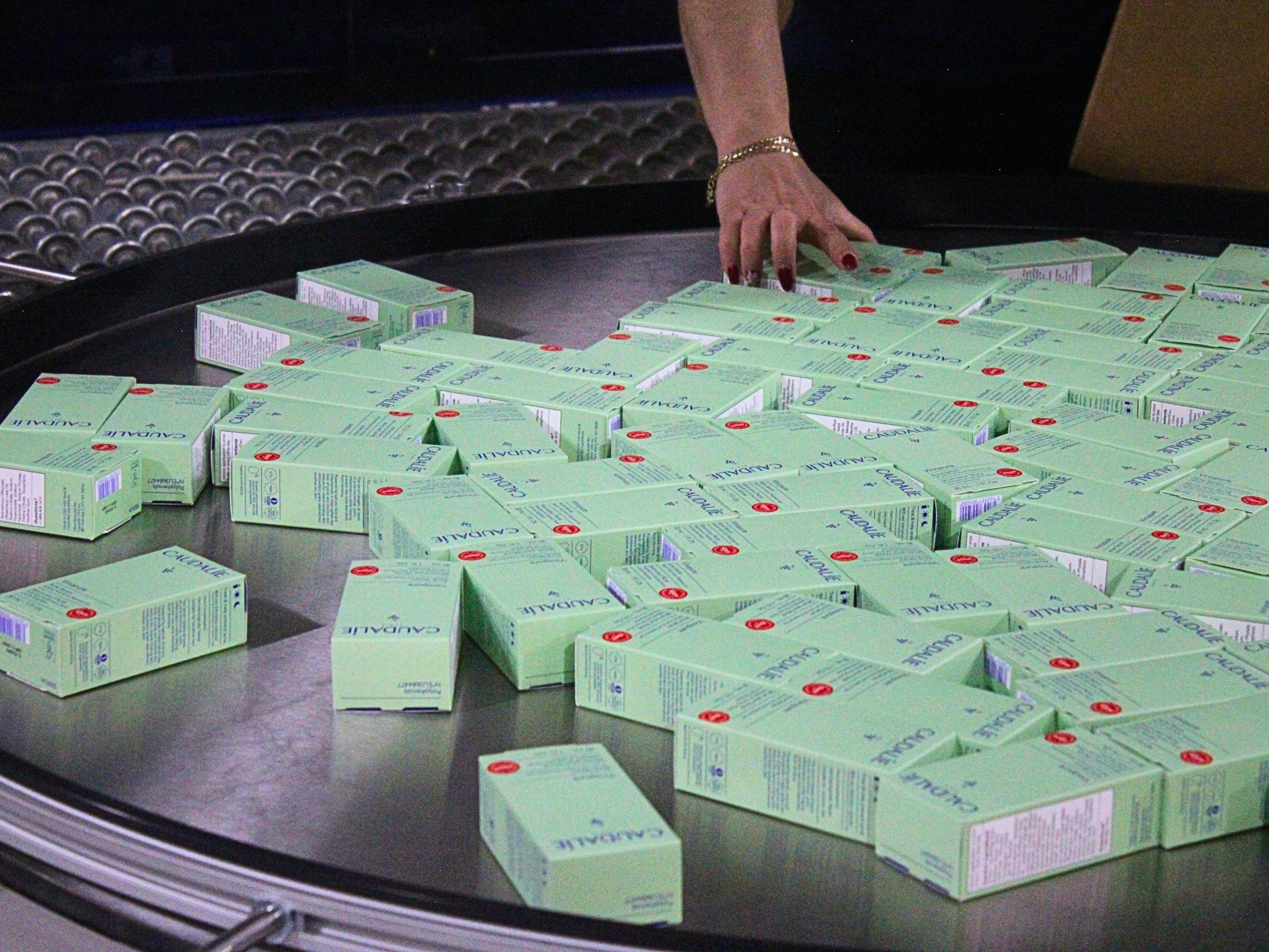 Operator handling packaged Caudalie products at an accumulation table