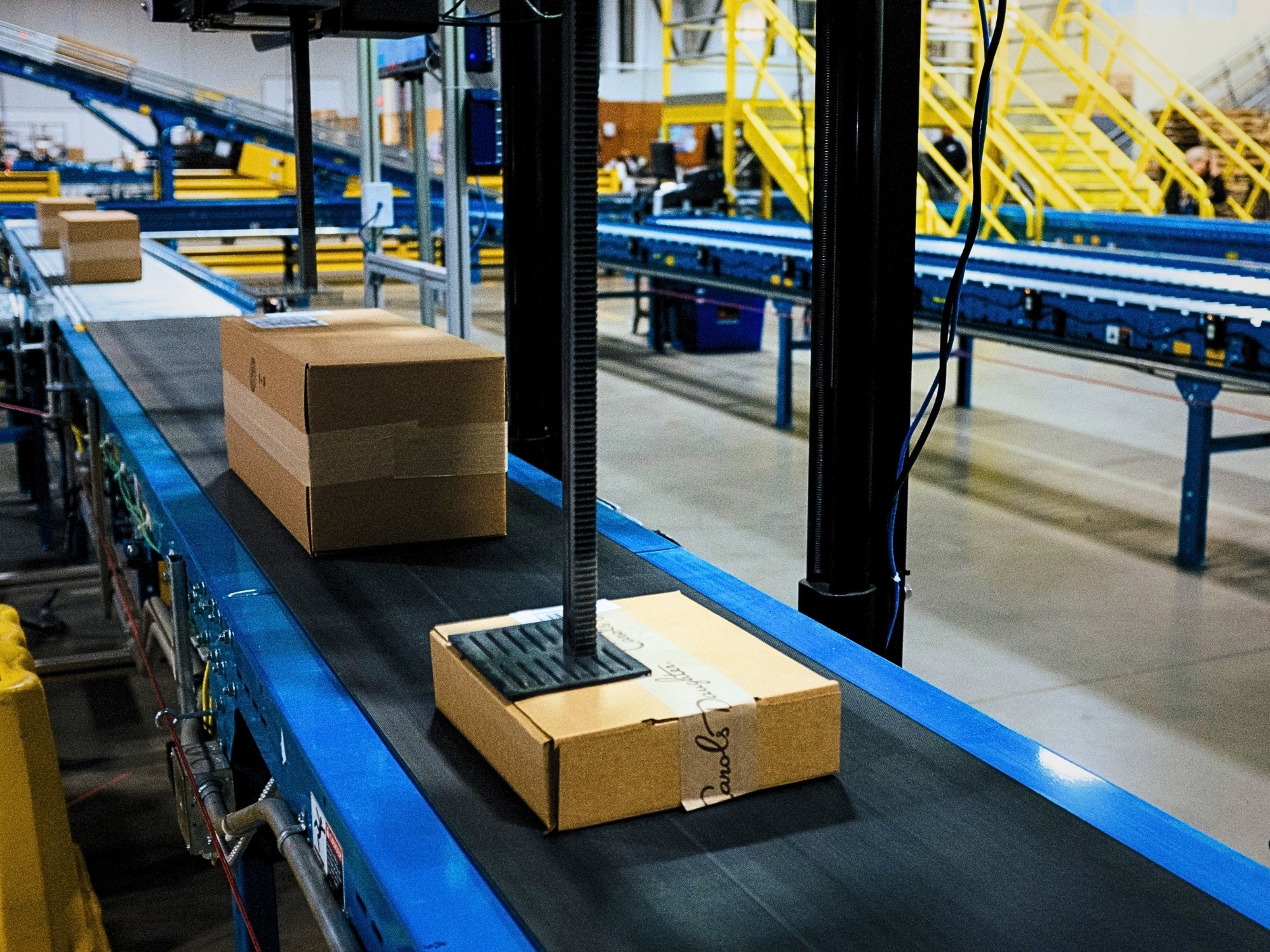 Tamp label applicator positioned over a carton to apply a shipping label on the conveyor