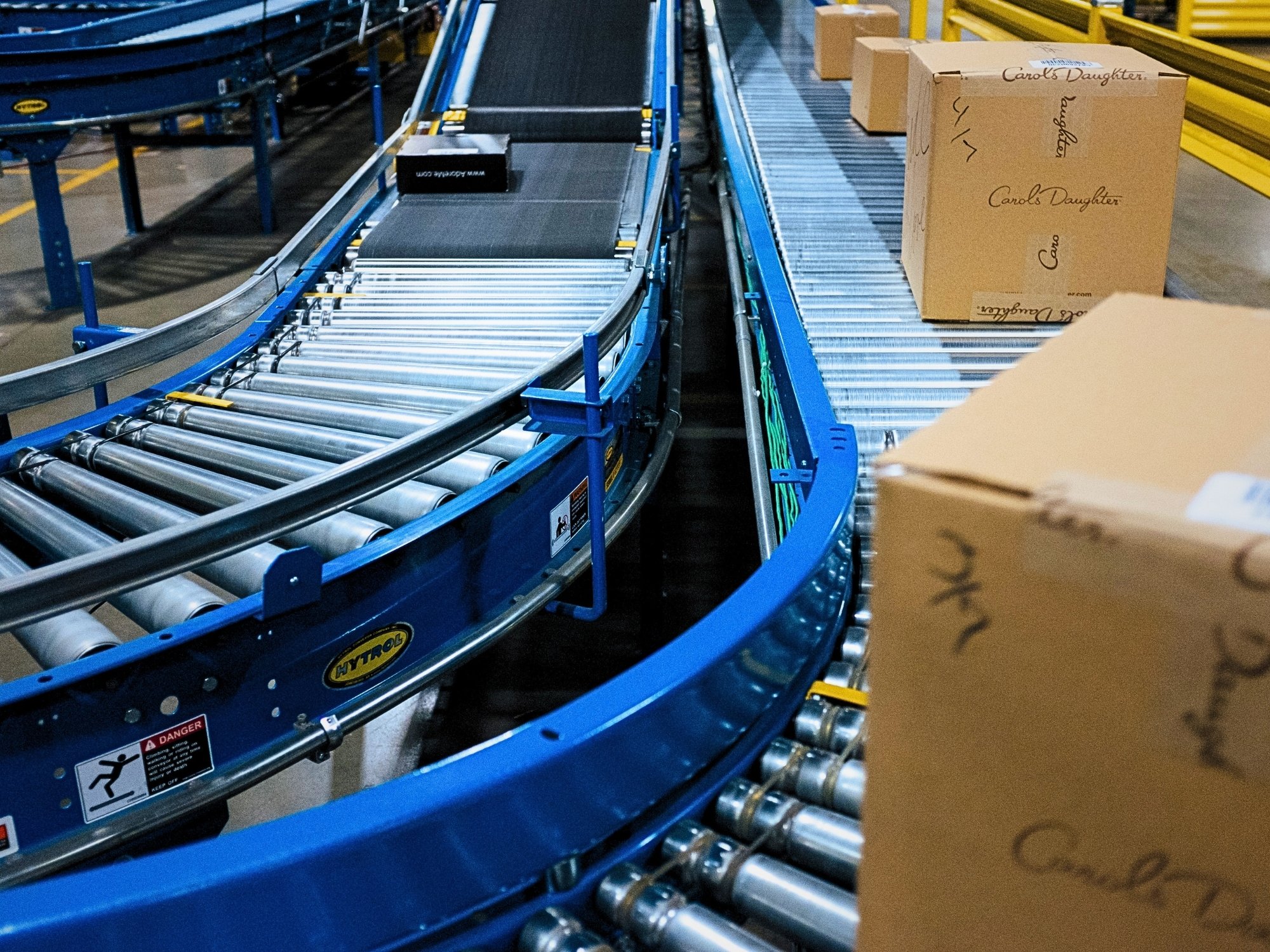 Curved roller conveyor beside a straight carton lane, connecting different conveyor lines