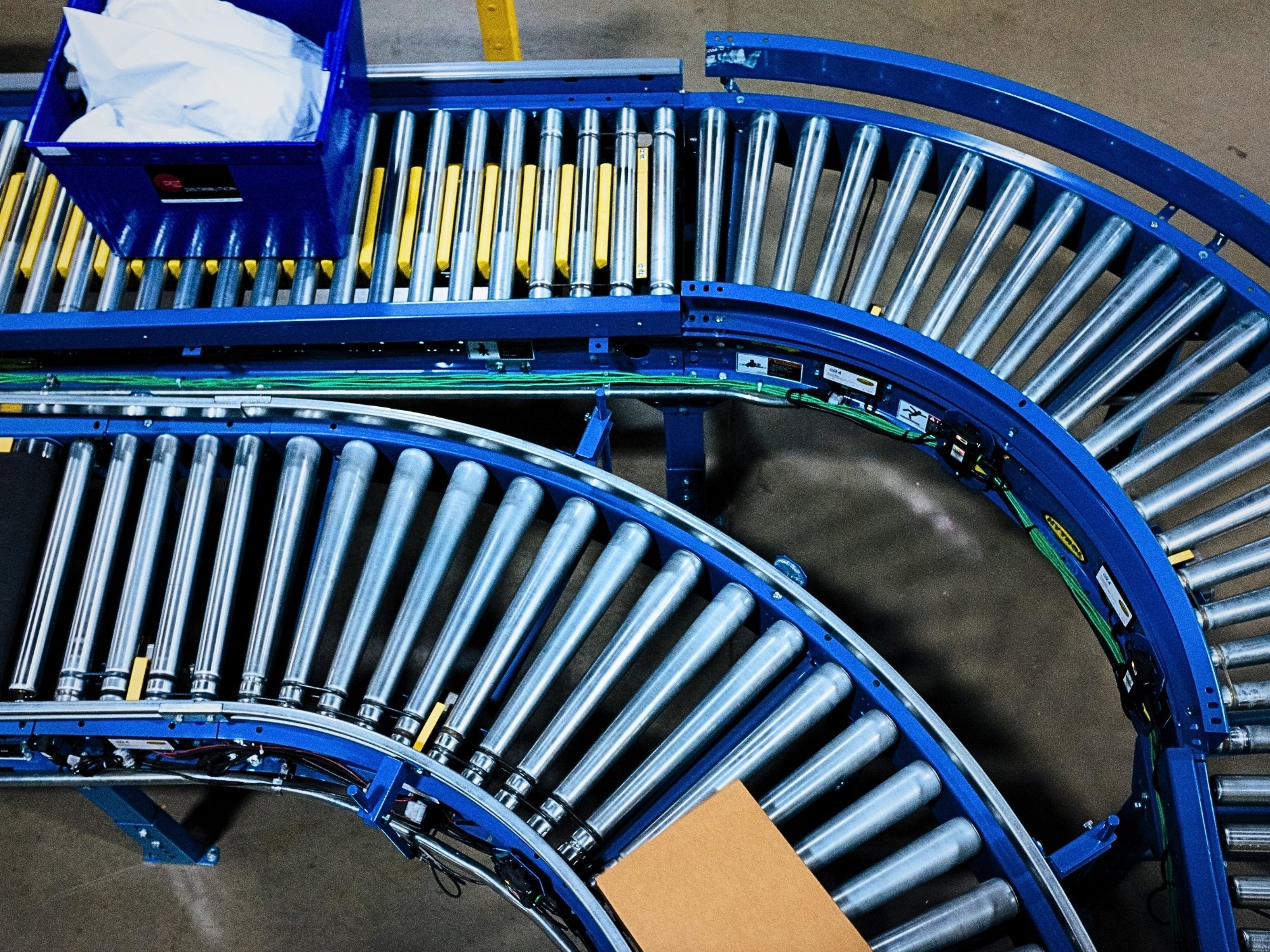 Overhead view of adjacent curved roller conveyor lanes that redirect carton flow