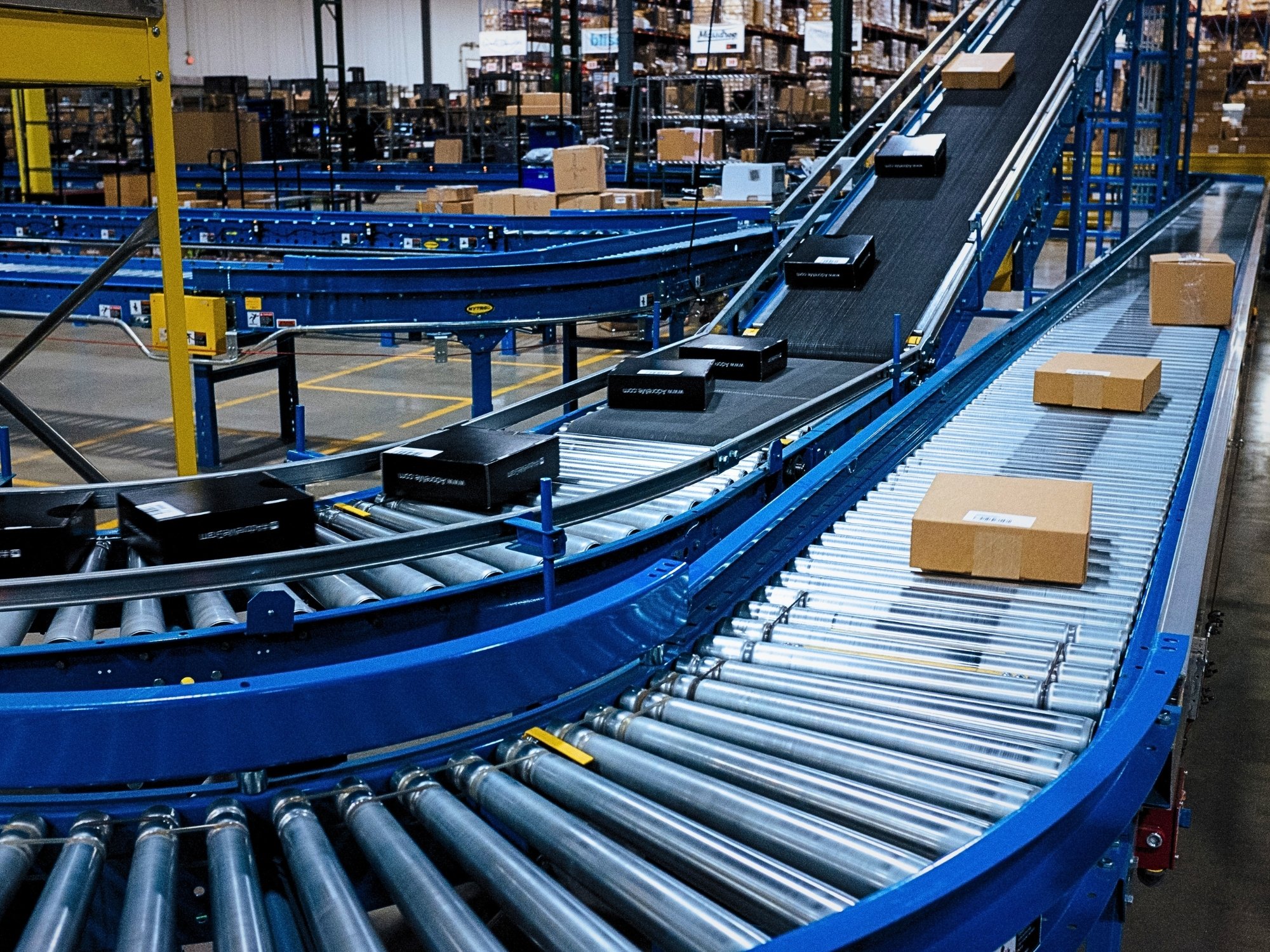 Parallel curved roller conveyors connecting carton transport lanes with inclined conveyor sections