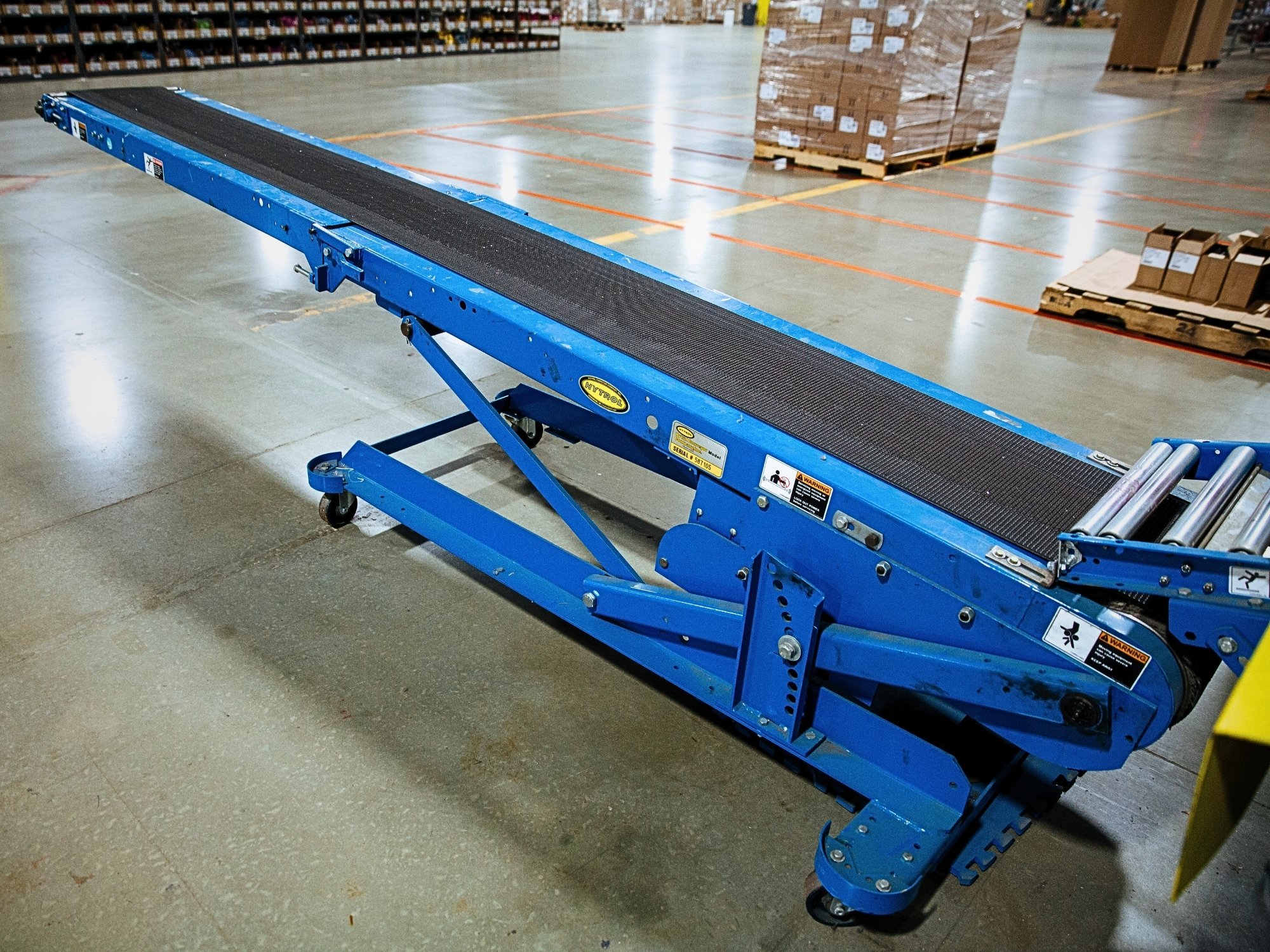 Mobile incline belt conveyor connected to a roller conveyor section for carton transfer