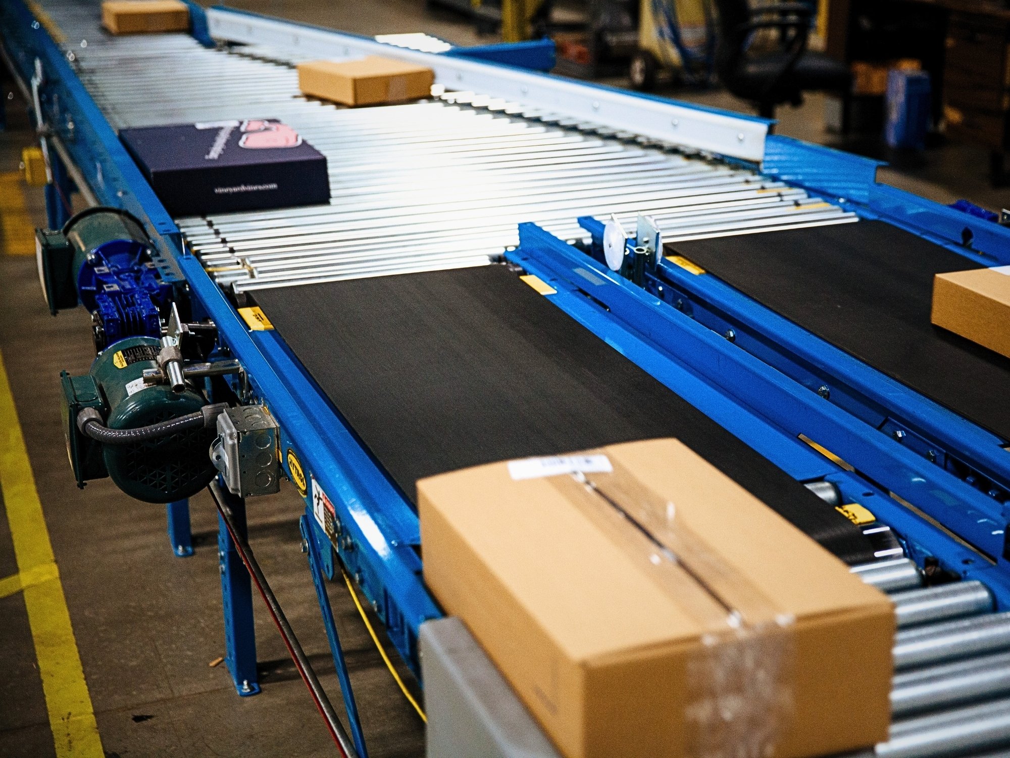Carton moving across a belt conveyor section at a transition to roller conveyor